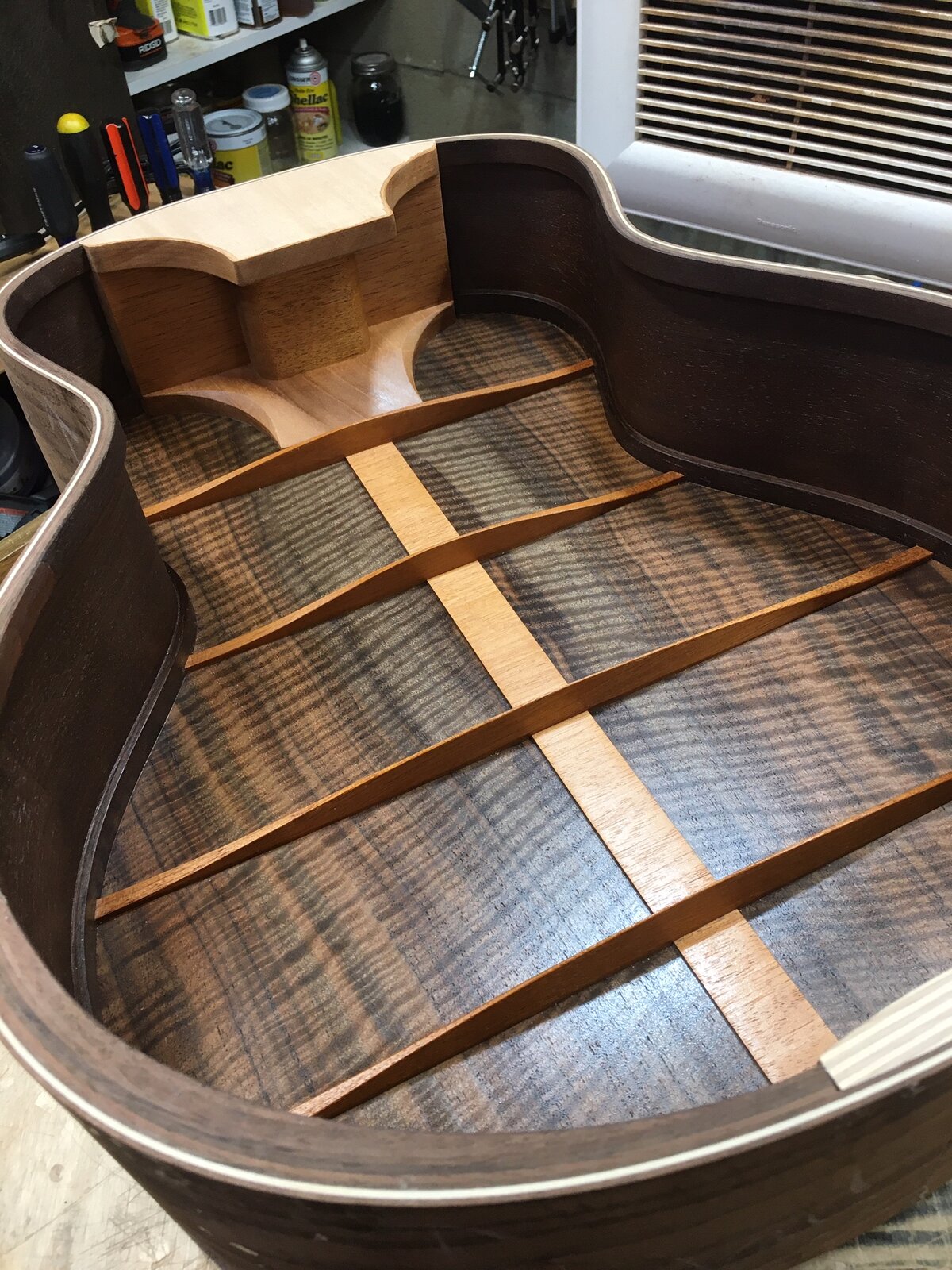 The inside of the guitar body during the build, showing the bracing on the walnut back
