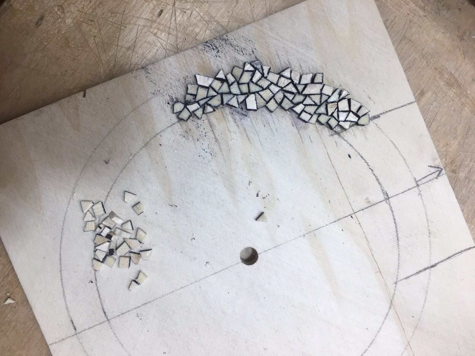 Small tiles of mammoth fossil ivory being arranged into the rosette mosaic